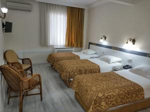 a hotel room with three beds and two chairs at Hali Hotel in Istanbul