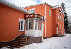an orange building with a white door in the snow at Hotel Complex Olimp in Umanʼ