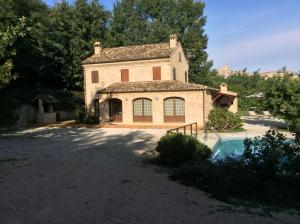 uma grande casa de pedra com uma piscina em frente em Villa Santa Maria em Montegiorgio