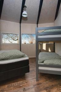 two bunk beds in a room with two windows at Dobberhuisje in Nieuwkoop