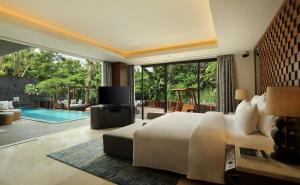 a bedroom with a bed and a television and a pool at Anantara Uluwatu Bali Resort in Uluwatu