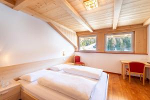 a bedroom with two beds and a table and a window at Gasthof Specker in Obereggen