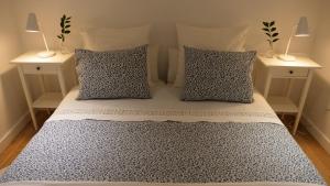 a bedroom with a bed with pillows and two night stands at Casiñas Mariñeiras (Taberna Vella) in Portosin