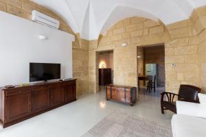uma sala de estar com televisão e uma parede de pedra em Casa Florean Centro Storico Lecce em Lecce