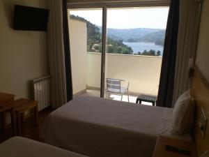 een hotelkamer met een bed en een groot raam bij Hotel Lagoa Azul do Geres in Geres