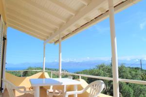 patio con mesa y sillas en el balcón en Lefkothea Apartments en Kassiopi