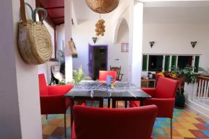 a dining room with a table and red chairs at Dar Zerhoune in Moulay Idriss