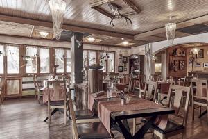 een restaurant met houten tafels, stoelen en ramen bij Hotel Marmotte in Saas-Fee