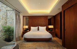 a bedroom with a large bed with white pillows at Anantara Uluwatu Bali Resort in Uluwatu