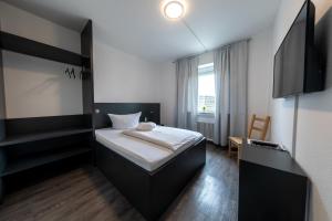 ein kleines Zimmer mit einem Bett und einem Fernseher in der Unterkunft Hotel Central in Menden