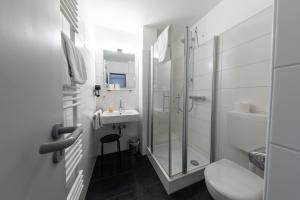uma casa de banho com um chuveiro, um WC e um lavatório. em Hotel Central em Menden