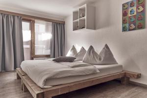 een slaapkamer met een bed met witte lakens en kussens bij Hotel Marmotte in Saas-Fee