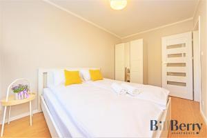 sypialnia z dużym białym łóżkiem z żółtymi poduszkami w obiekcie Happy - BillBerry Apartments w mieście Gdynia