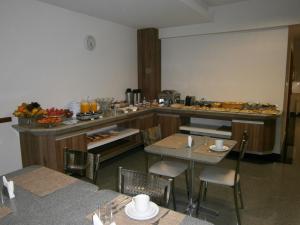 a kitchen with tables and a counter with food on it at Sete Lagoas Residence Hotel in Sete Lagoas