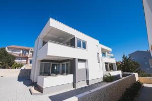 a white house with a blue sky at Apartments Tomana in Novalja