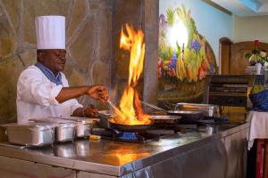 a man cooking food in a pan on a stove at Comfort Gardens in Nairobi