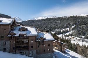 クールシュヴェルにあるKeystone Lodge by Alpine Residencesの山々を背景に雪に覆われた建物