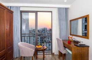 una camera d'albergo con balcone arredato con tavolo e sedie di Royal Charm Hotel a Da Nang