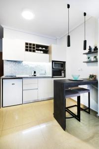 uma cozinha com armários brancos e uma mesa preta em Grey Rhino 1min From The White Tower em Tessalônica