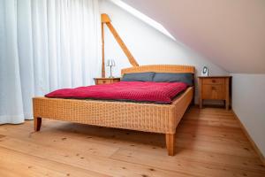 Cama de mimbre en una habitación con suelo de madera en Roger`s Ferienwohnung, en Dießen am Ammersee