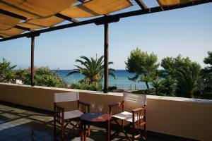 a table and chairs on a balcony with a view of the beach at ENJOY A BEACH HOLIDAY in Livadhákia
