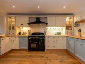 a kitchen with white cabinets and a black stove at Stunning Farm Steading - 5 Mins to St Andrews in St Andrews