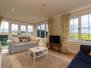 a living room with a couch and a tv and windows at Stunning Farm Steading - 5 Mins to St Andrews in St. Andrews