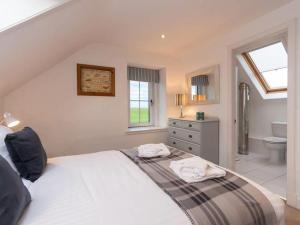 a bedroom with a white bed and a bathroom at Stunning Farm Steading - 5 Mins to St Andrews in St Andrews