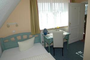 a bedroom with a bed and a table and a window at Landhotel Ostseetraum & Apartments in Warnemünde