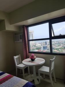 Zimmer mit einem Tisch, 2 Stühlen und einem Fenster in der Unterkunft Horizon 101 Cebu by KC Condo in Cebu City