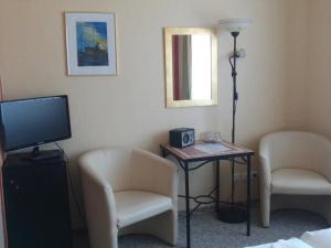 Zimmer mit 2 Stühlen und einem Tisch mit einem TV in der Unterkunft Landhotel Ostseetraum & Fewo in Warnemünde