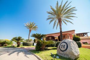 a house with palm trees and a rock in front of a house at TH San Teodoro - Liscia Eldi Village in San Teodoro