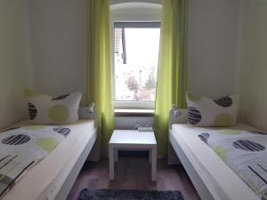 two beds in a small room with a window at City-Apartment in Sinsheim