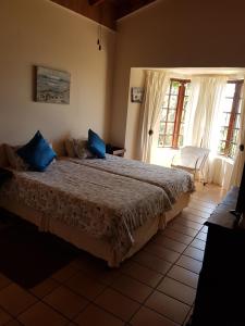 ein Schlafzimmer mit einem großen Bett mit blauen Kissen darauf in der Unterkunft Fig Tree Manor Self Catering in Blythedale