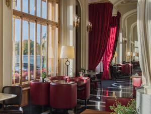 ein Restaurant mit roten Stühlen, Tischen und Fenstern in der Unterkunft Angleterre Hotel in Sankt Petersburg