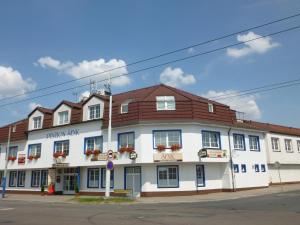 un grand bâtiment blanc avec un toit marron dans l'établissement Penzion Šenk Pardubice, à Pardubice