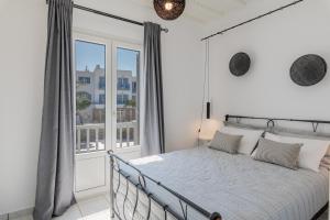 a bedroom with a bed and a large window at Secret Garden Apartments in Mikonos