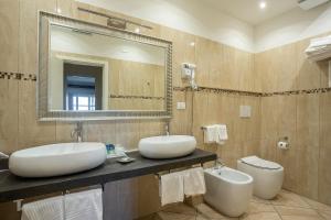 a bathroom with two sinks and a mirror and a toilet at Hotel Rex in Livorno