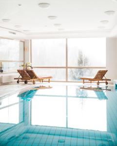 a swimming pool with two benches in a building at Hotel Triglav in Bled