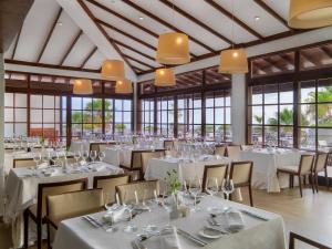 a dining room with white tables and chairs and windows at Hotel Jardín Tecina in Playa de Santiago