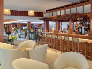a restaurant with a bar with white chairs and tables at Hotel Jardín Tecina in Playa de Santiago