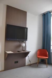 a room with a red chair and a tv on a wall at Les Tonnelles in Bar-sur-Seine