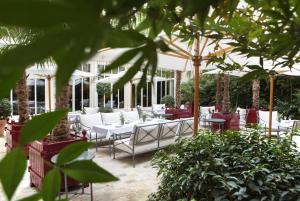 um pátio com cadeiras brancas, mesas e árvores em La Réserve Paris Hotel & Spa em Paris