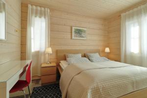 1 dormitorio con 1 cama y escritorio con silla roja en Villa Maria Cottages, en Jaala