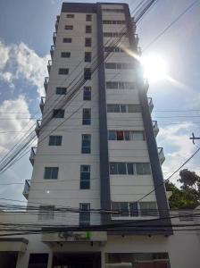 a tall white building with the sun behind it at Cityscape Residences, Unit 702 in Bacolod