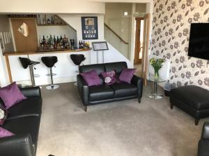 a living room with a black leather couch and purple pillows at Cotswold House in Falmouth