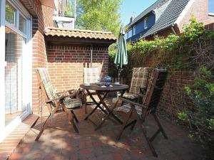 eine Terrasse mit einem Tisch, 2 Stühlen und einem Sonnenschirm in der Unterkunft Haus Kiebitznuest - Langeoog in Langeoog