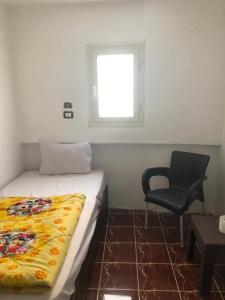 ein Schlafzimmer mit einem Bett, einem Stuhl und einem Fenster in der Unterkunft Colour Holidays in Kairo