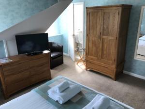 a bedroom with a bed and a tv and a dresser at Cotswold House in Falmouth