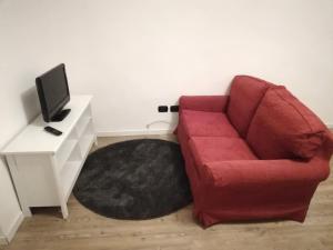 a living room with a red couch and a tv at CENTRO e PARCO 10 min - flat in Monza in Monza